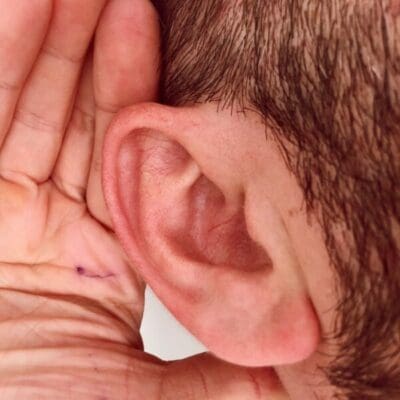 Close up of a man's ear with his hand cupped against it