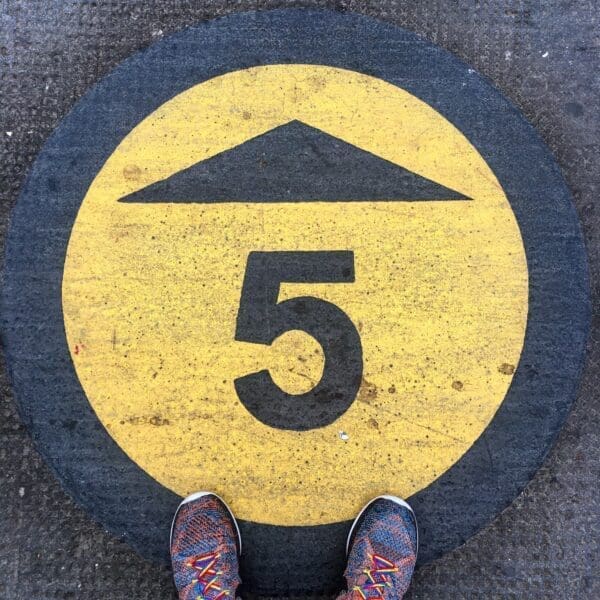 Number painted in black and yellow paint on pavement with two shoe fronts
