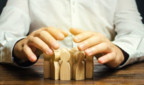 Businessman with his hands over wooden figures represents a leader