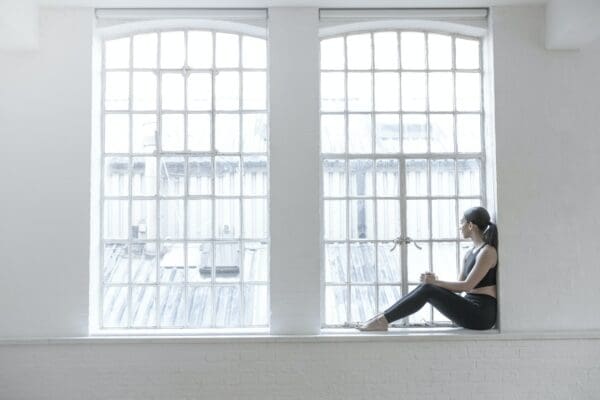 Woman sitting on windowsill to deal with trauma at work