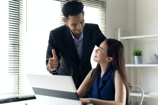 Business man mentoring female colleague at her desk