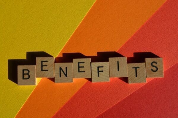 Benefits spelled with wooden alphabet letters isolated on sun ray colors background