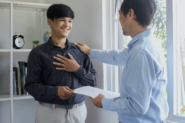 Boss praising male employee with hand on shoulder