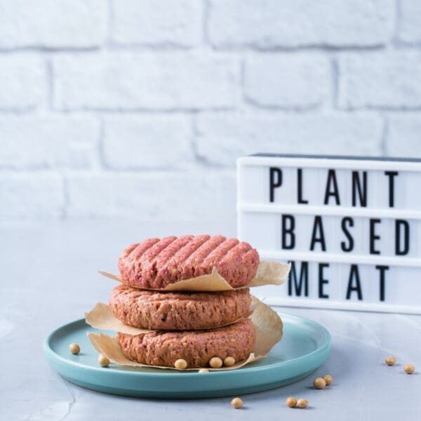 Stack of plant-based burger meat on a blue plate with soy beans