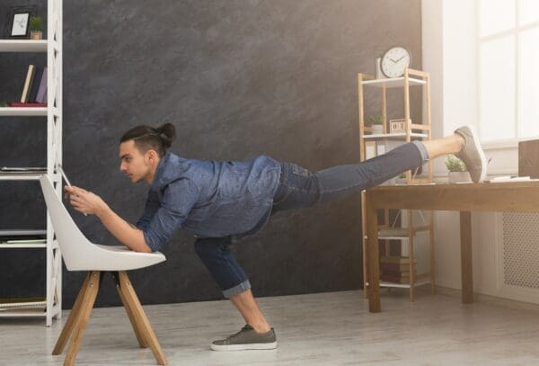 Flexible man practicing yoga at workplace