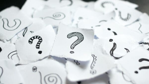 Many doodle drawn question marks on scraps of paper.