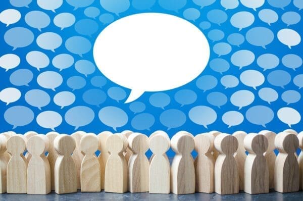 Wooden figures with speech bubbles above them for communication channels