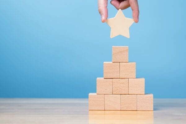 hand putting star on wood block to employee reward system