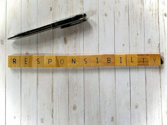 Responsibility spelled with wooden word scramble cubes next to a balck pen
