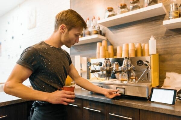 Young worker making coffee with a machine