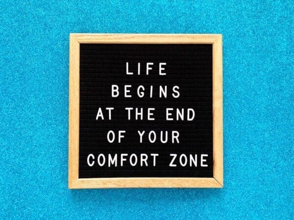 Life begins at the end of your comfort zone framed quote on blue background