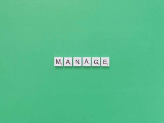 Manage written in scrabble tiles on a green background 