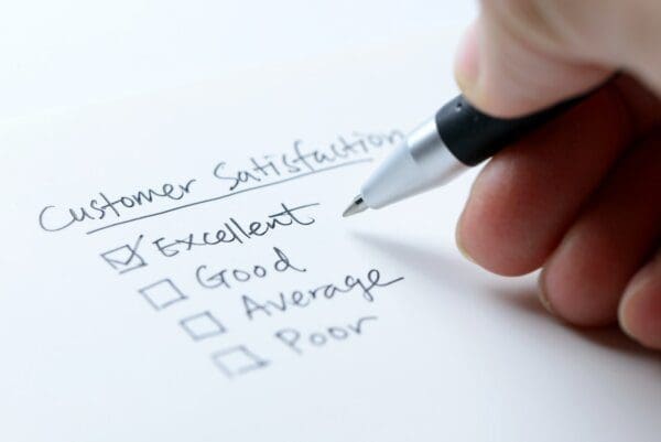 Hand with pen completing a customer satisfaction questionnaire with an excellent rating