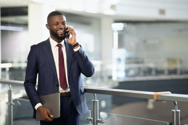 Happy handsome black businessman talking on phone, busienss center interior