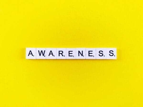 Awareness spelled with word scramble cubes on a yellow background 
