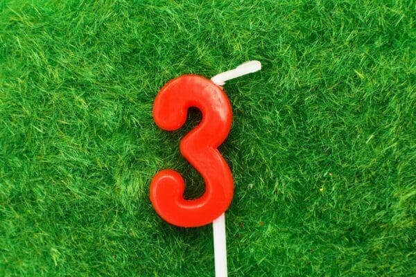Red number 3 candle on green grass