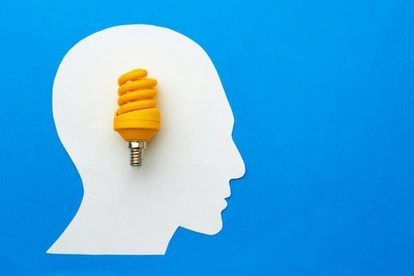 Papercut head and light bulb on blue background