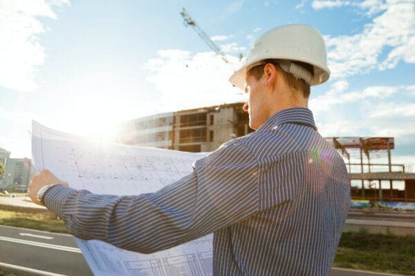 Architect in helmet with blueprints looks at camera in a building site for mbti articles