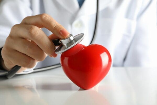 Doctor's hand using statoscope to check a red heart beat