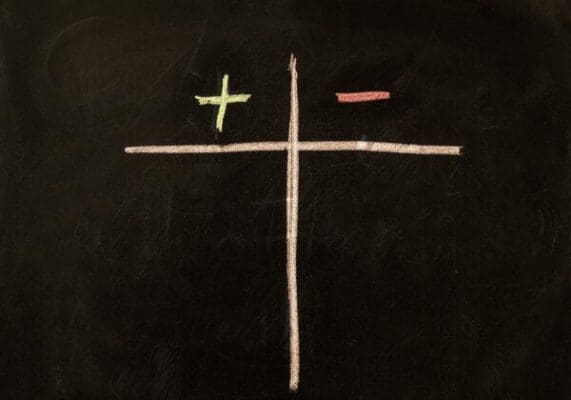 Plus and minus signs drawn on a chalkboard represents pros and cons