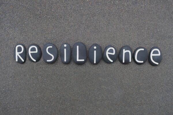 Resilience spelled with white letters on rocks on the sand