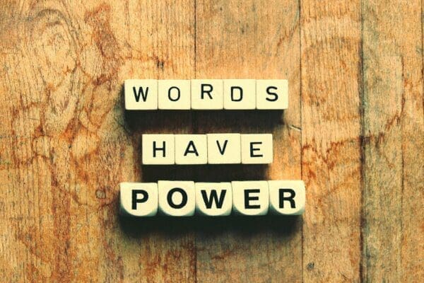 Words have power spelled with wooden scramble cubes on a wooden surface
