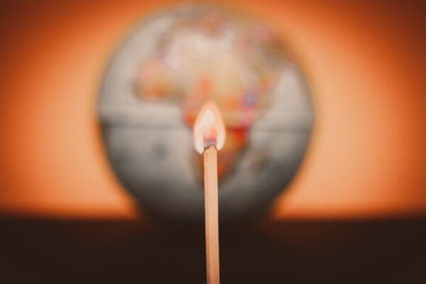 Burning match on blurred world globe background