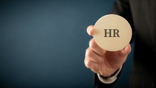 Businessman holding a wooden cut circle with HR letters to represent the Human Resource job function