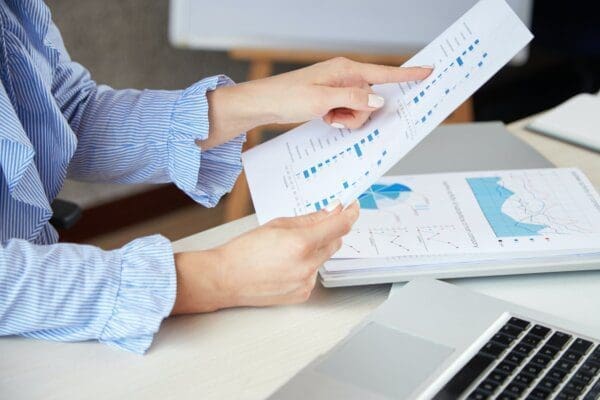 Close up of businesswoman's hands analysing chart documents at her desk