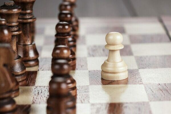 White chess piece separated from brown chess piece on chessboard