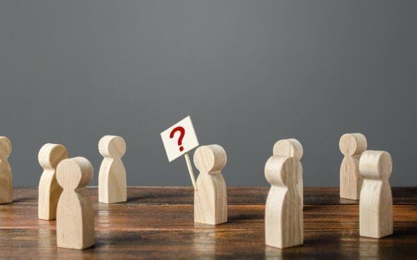 Wooden figures on the table with one holding a question mark sign