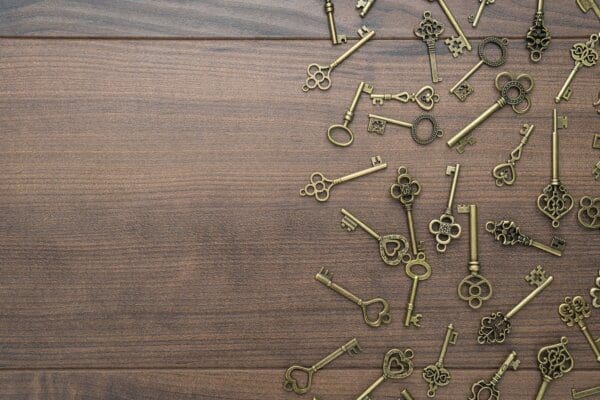Many gold vintage keys spread out on a wooden table