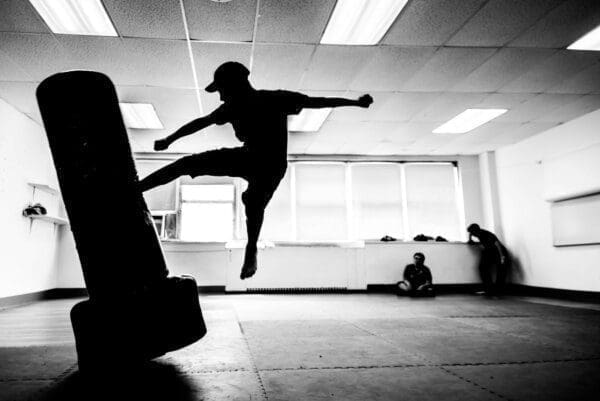 Silhouette of a man jump kicking a punch bag