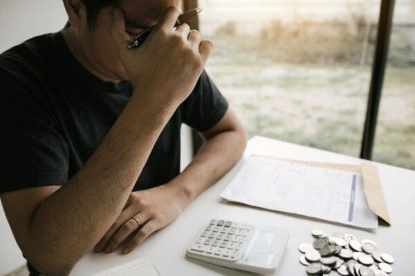Man stressed about from financial problems with invoices and calculators at his desk