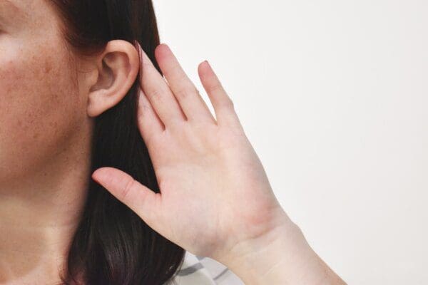 Close up of woman's ear with her hand behind it 