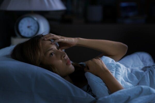 Young woman lying in bed at night with insomnia