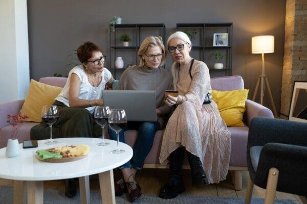 3 entp women sat on the sofa looking at a laptop and a phone