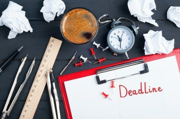 Deadline written on a red clipboard with stationary around it