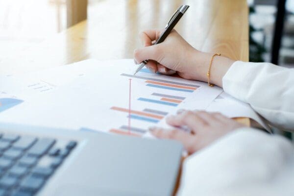 Woman's hand using a pen to write on high performance marketing data chart