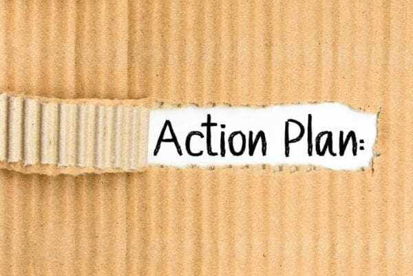 Action plan text visible behind a torn cardboard paper