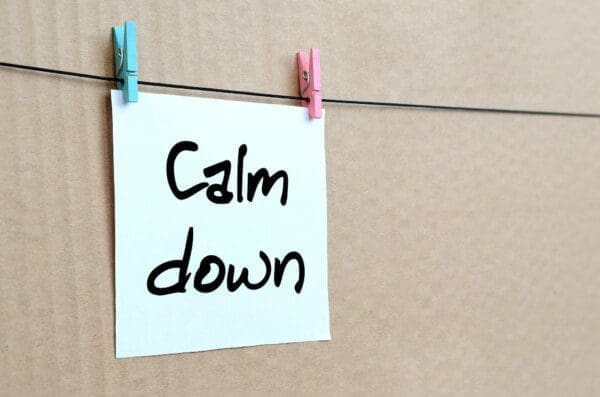 Calm down written in black on a post it note pegged to a line