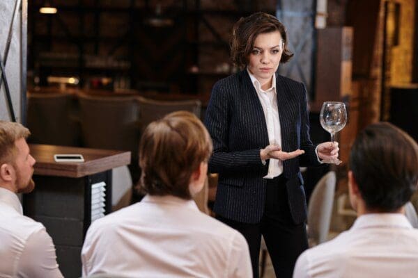 Confident restaurant manager briefing employees on menu while holding a wine glass