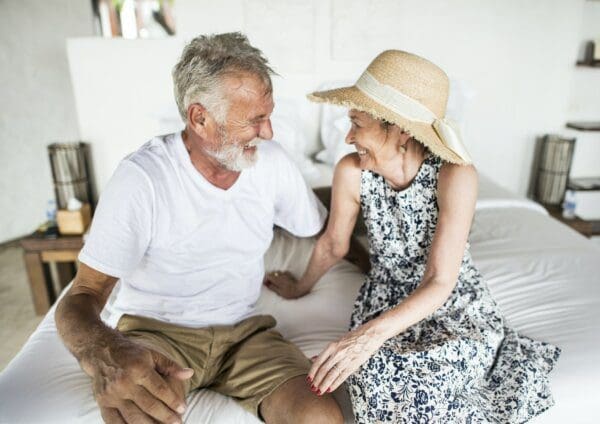 old couple smiling at each other on the bed