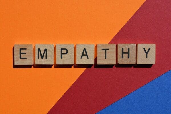 Empathy written in wood letters across a coloured background