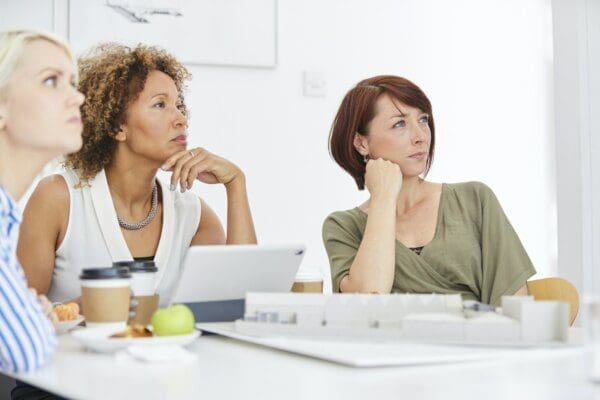 3 female coworkers listening to another colleague during a meeting