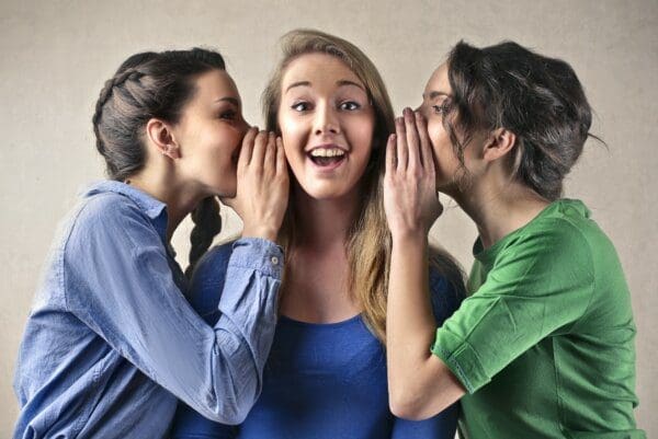 Two girls telling secrets to a happy ENFJ girl in the middle 