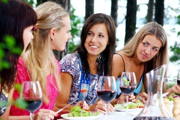Group of young women sat at a table drinking wine