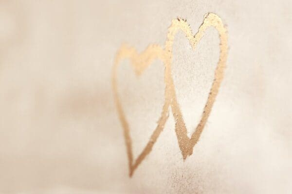 Two gold hearts intertwined on a white wall