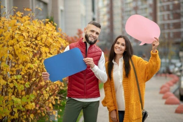 Joyful happy couple participating in social campaign holding cutout speech bubbles for mbti articles