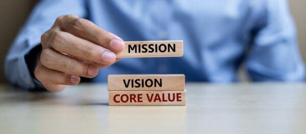 Businessman putting Mission, Vision, and Core Value blocks on top of each other